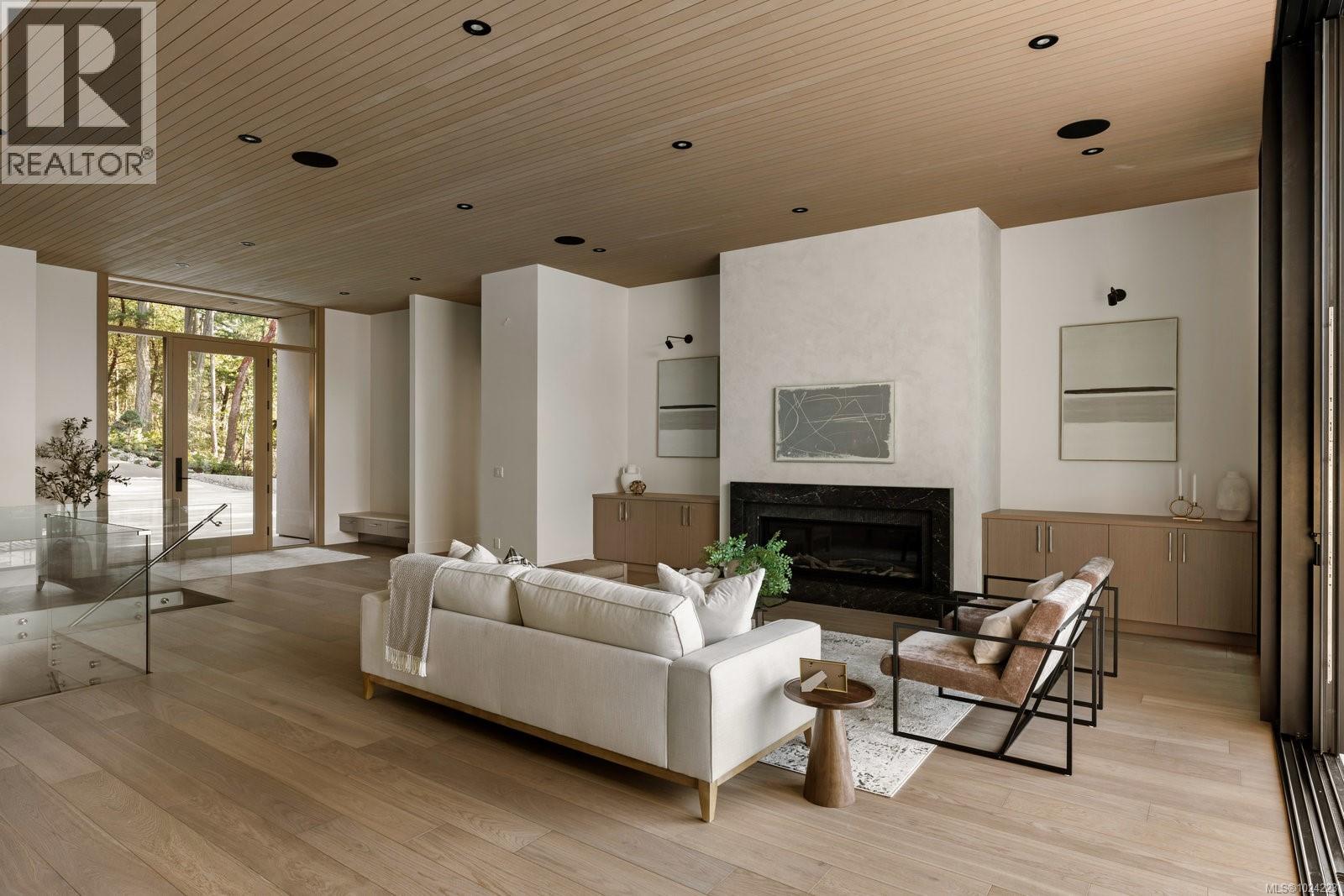 Open concept living room with floor-to-ceiling windows overlooking the ocean, hardwood floors and modern furnishings