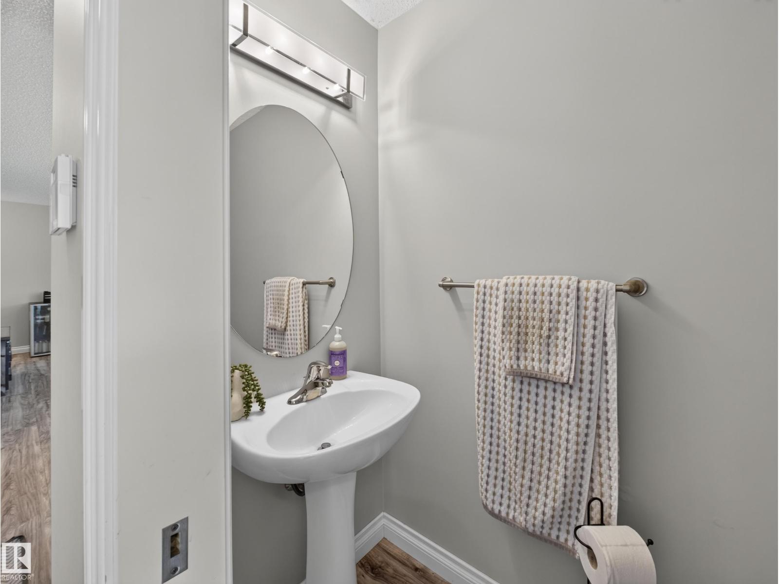 Powder room with pedestal sink and oval mirror