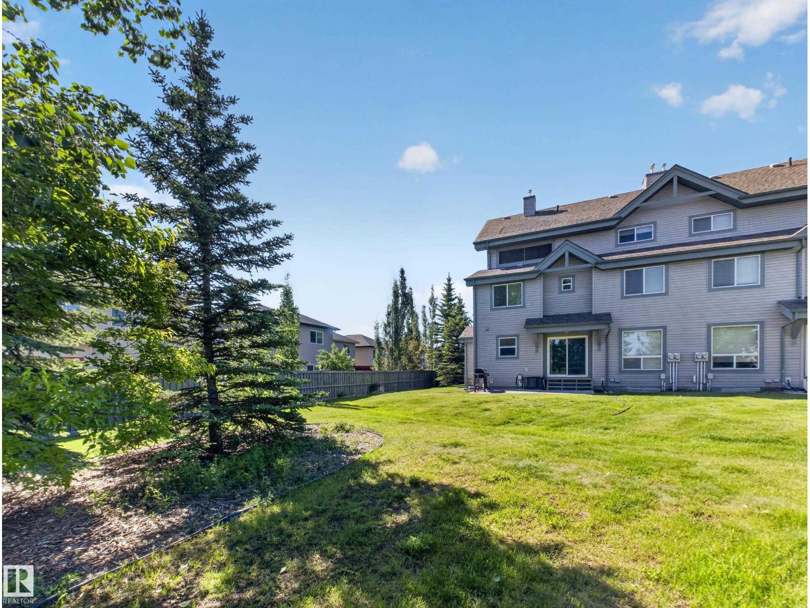 Rear exterior across the back lawn with mature spruce