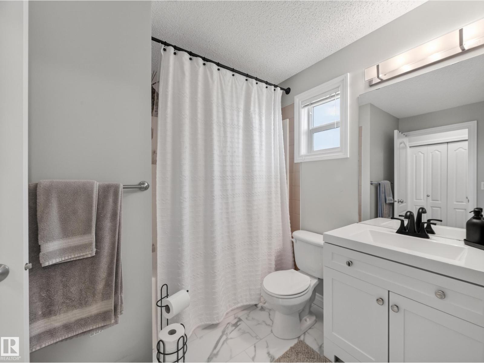 Main bath with tub and shower, vanity and marble-look floor