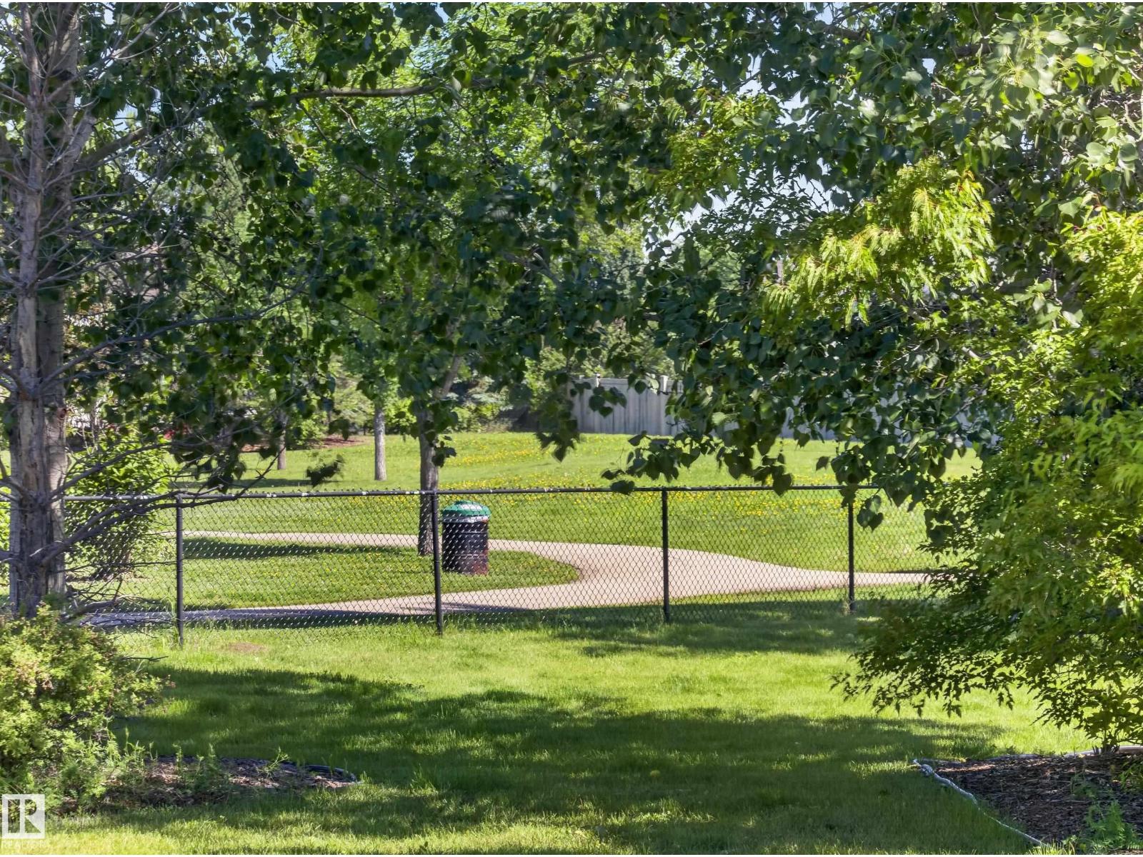 Green space with the walking path, trees and fence line